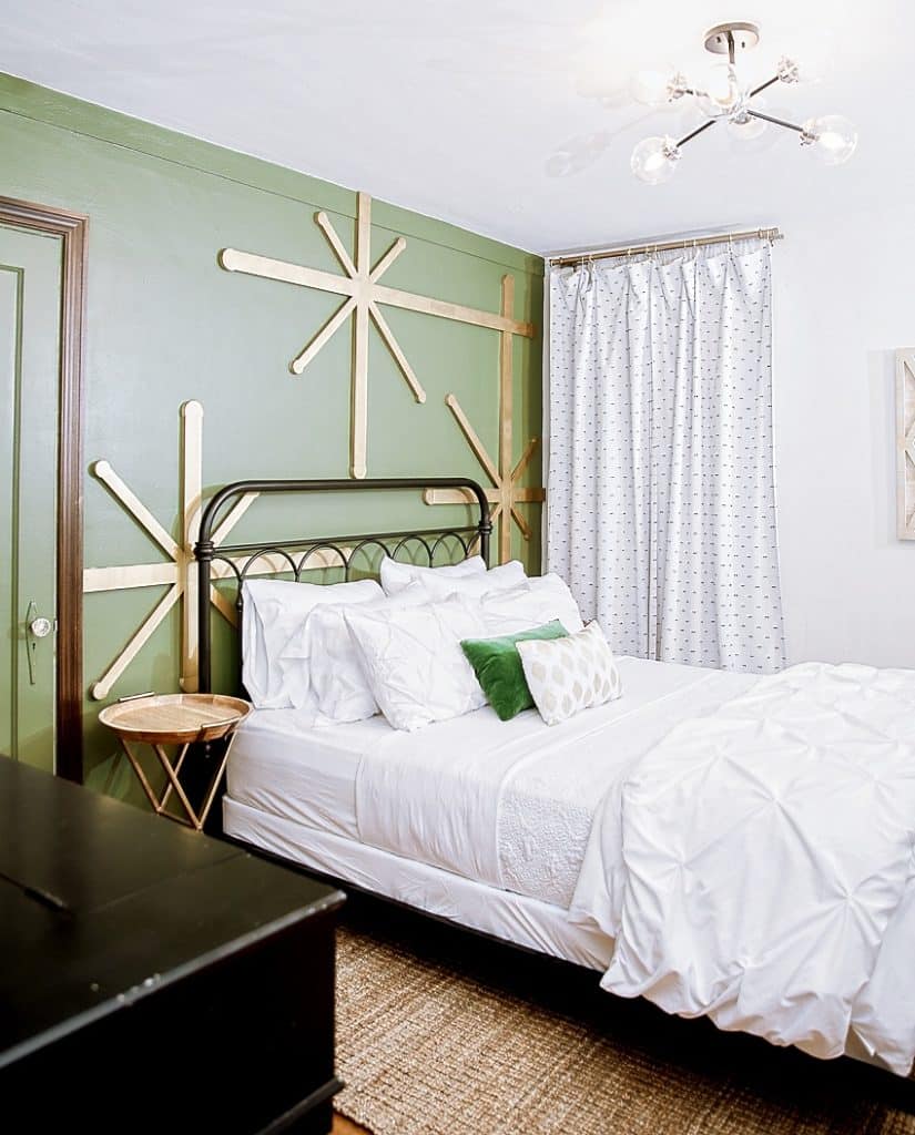 Bedroom with green wall, large gold stars, and a Queen size bed with white bedding on a sisal rug