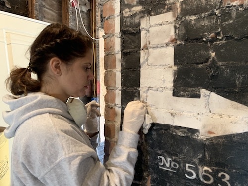 sanding_old_ad_painted_on_brick_chimney