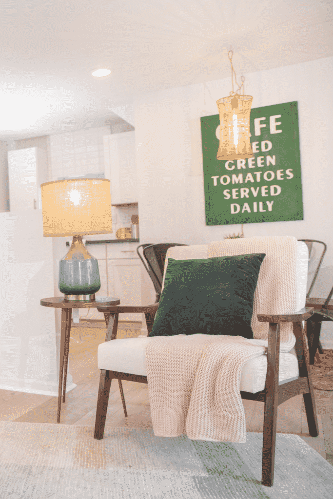 A living room with a small chair, table, and reading lamp. 