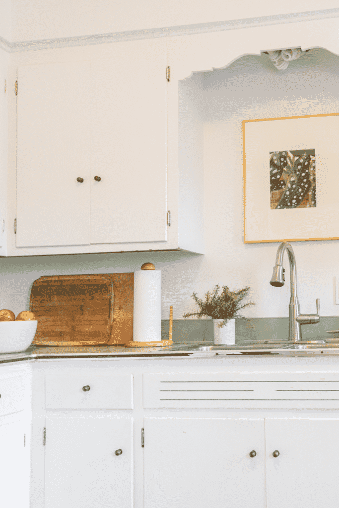 A kitchen corner with a sink and white cabinets. 