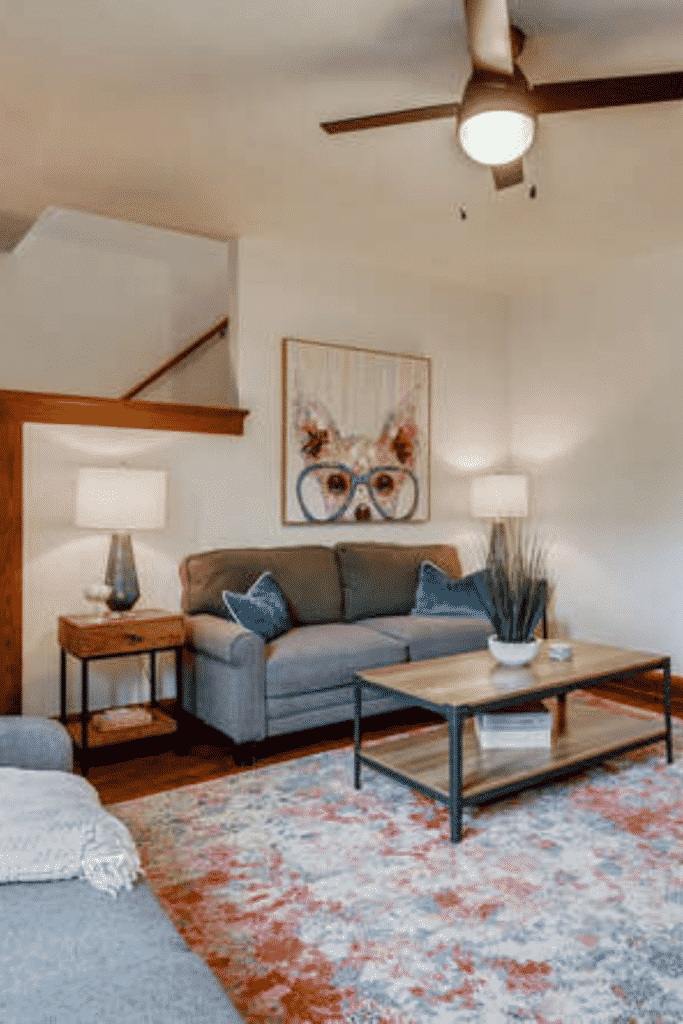 A living room with a ceiling fan light, couches, coffee table, and a dog painting.