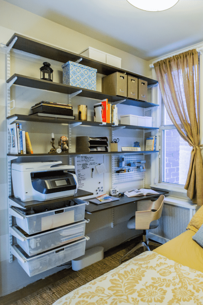 Several wall shelves on the side of a bedroom that serves as an office space.