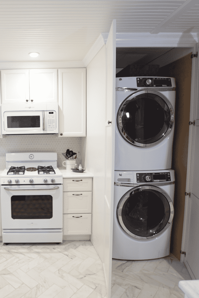 A kitchen with a white stove, oven, and microwave, next to a closet with a stacked washer and dryer.