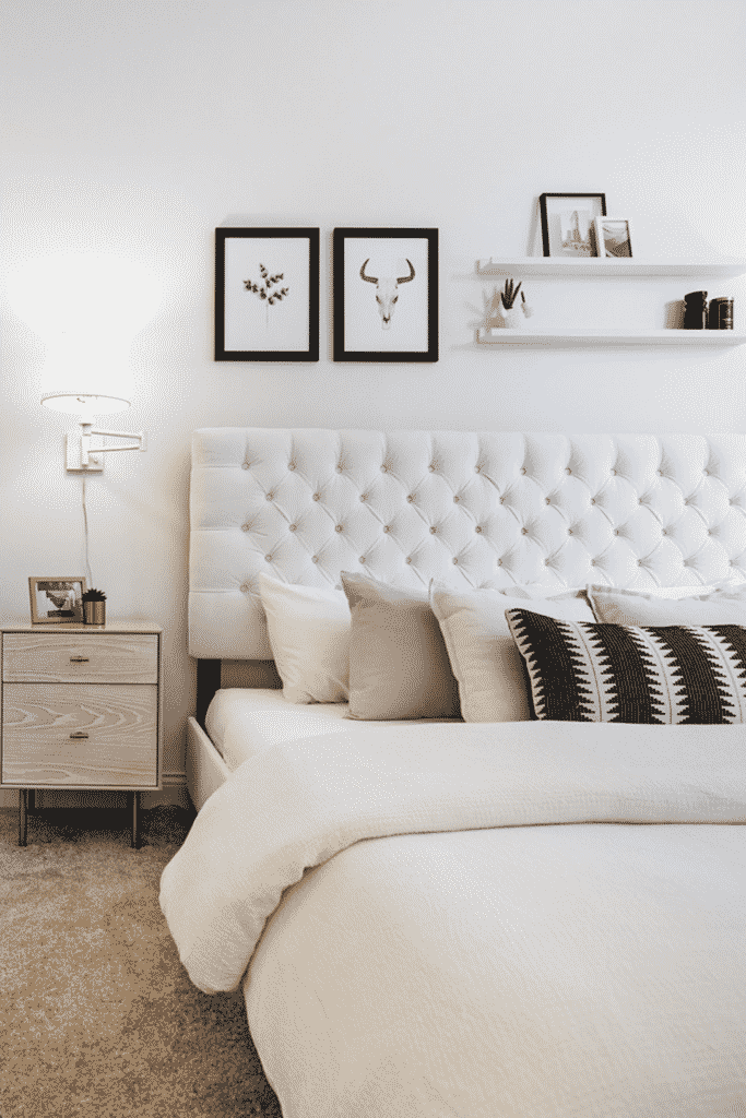 A bedroom with a white bed and wooden nightstand.