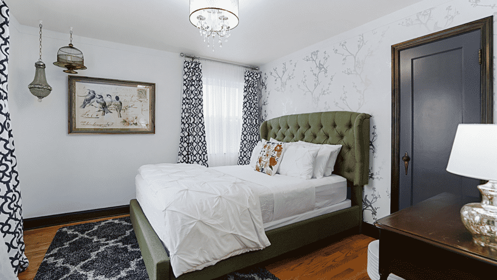 Tastefully decorated Airbnb bedroom with large green upholstered headboard on bed.