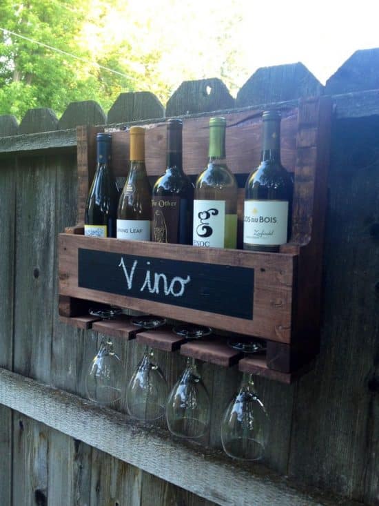 Small wooden wine rack attached to wooden fence.